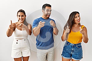 Group of young hispanic people standing over isolated background pointing fingers to camera with happy and funny face