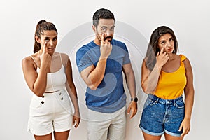 Group of young hispanic people standing over isolated background pointing to the eye watching you gesture, suspicious expression