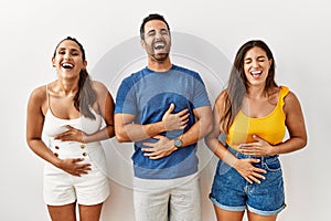 Group of young hispanic people standing over isolated background smiling and laughing hard out loud because funny crazy joke with