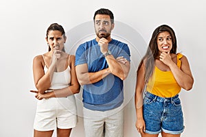 Group of young hispanic people standing over isolated background thinking worried about a question, concerned and nervous with
