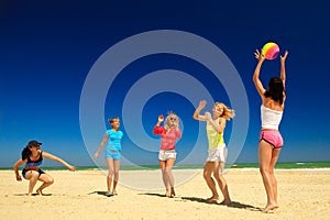 Group of young joyful girls playing volleyball