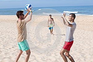 Group young joyful girls playing volleyball on beach