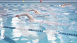 Group of young male athletic professional swimmers having training crawl at waterpool