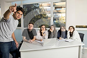 Group of young male and female teenager university students at school sitting on classroom learning and working on project togethe