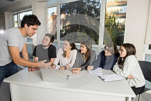 Group of young male and female teenager university students at school sitting on classroom learning and working on project togethe