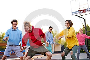 Group of young male teenagers playing basketball outdoors