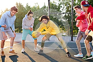 Group of young male teenagers playing basketball outdoors