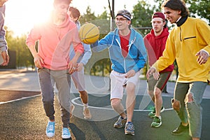 Group of young male teenagers playing basketball outdoors