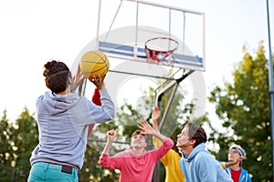 Group of young male teenagers playing basketball outdoors