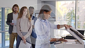 Group of young managers standing in queue for copier at office