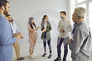 Group of young and mature business people standing and talking during meeting in office