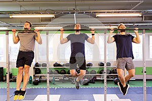 Group of young men doing pull-ups in gym