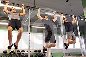 Group of young men doing pull-ups in gym