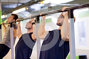 Group of young men doing pull-ups in gym