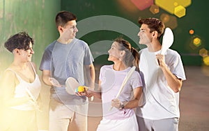 Group of young men and women having conversation about paleta fronton game on court