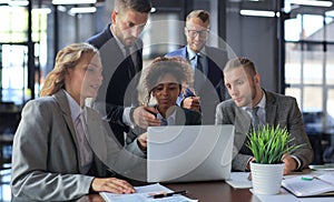 Group of young modern people in formalwear smiling and discussing something while working in the modern office