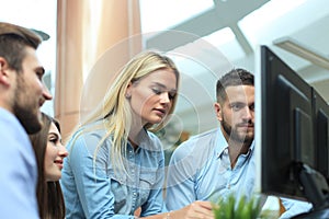 Group of young modern people in smart casual wear having a brainstorm meeting while standing in the creative office.