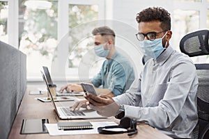 Group of young multi ethnic business people working in office wearing medical protective masks, Social distancing, teamwork