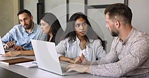 Group of young multiethnic colleagues engaged in teamwork using laptop