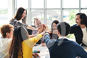Group of young multiethnic diverse people gesture hand high five, laughing and smiling together in brainstorm meeting at office. photo