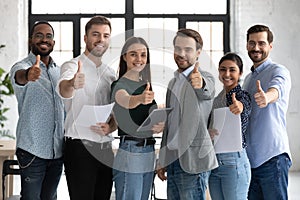 Group of young multiethnic employees standing together raising thumbs up