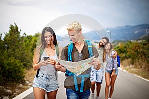 Group of young people with backpacks walking together by the road