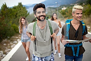 Group of young people with backpacks walking together by the road