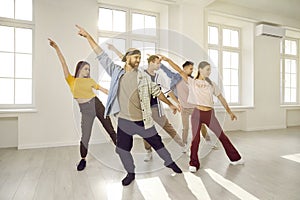 Group of happy young people having dancing class with dance instructor at the gym