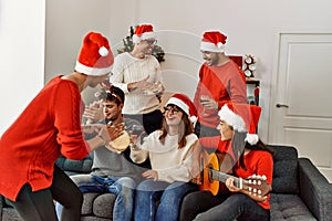 Group of young people celebrating christmas singing carol song at home