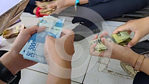 A group of young people are counting money at outdoor