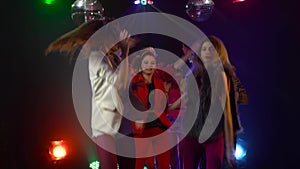 Group of young people dancing with raised arms to the music . Smoke background