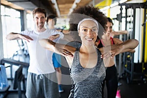 Group of young people doing exercises in fitness club