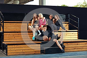 A group of young people have fun on the benches near the city sports ground. Young people, active lifestyle, lifestyle.