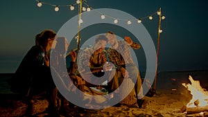 Group of young people having camp on the beach at night