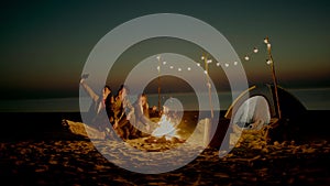 Group of young people having camp on the beach at night