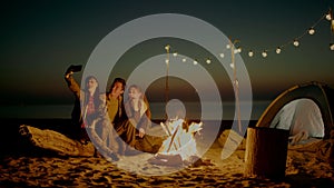 Group of young people having camp on the beach at night