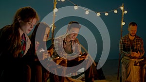 Group of young people having camp on the beach at night