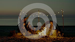 Group of young people having camp on the beach at night