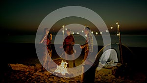 Group of young people having camp on the beach at night