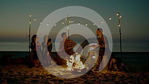 Group of young people having camp on the beach at night