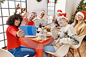 Group of young people having christmas dinner and video call using touchpad at home