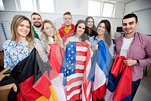 Group of young people holding international flags of many countries in the classroom