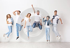 Group of young people in jeans jumping near wall