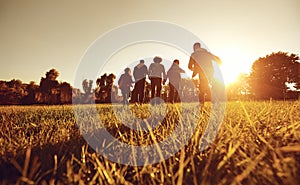 A group of young people running through the grass in the park at sunset.