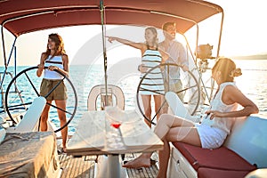Group of young people sailing on boat together and enjoy at sunset on vacation