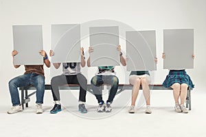 Group of young people sit holding, blank sign board studio shooting