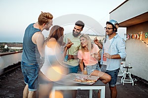 Group of young people sitting around and eating pizza