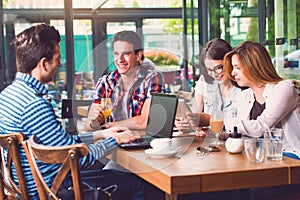 Group of young people sitting at a cafe, talking