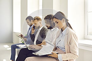 Group of young people sitting in office and waiting in line for their job interview