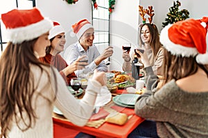 Group of young people smiling happy celebrating christmas toasting with wine at home